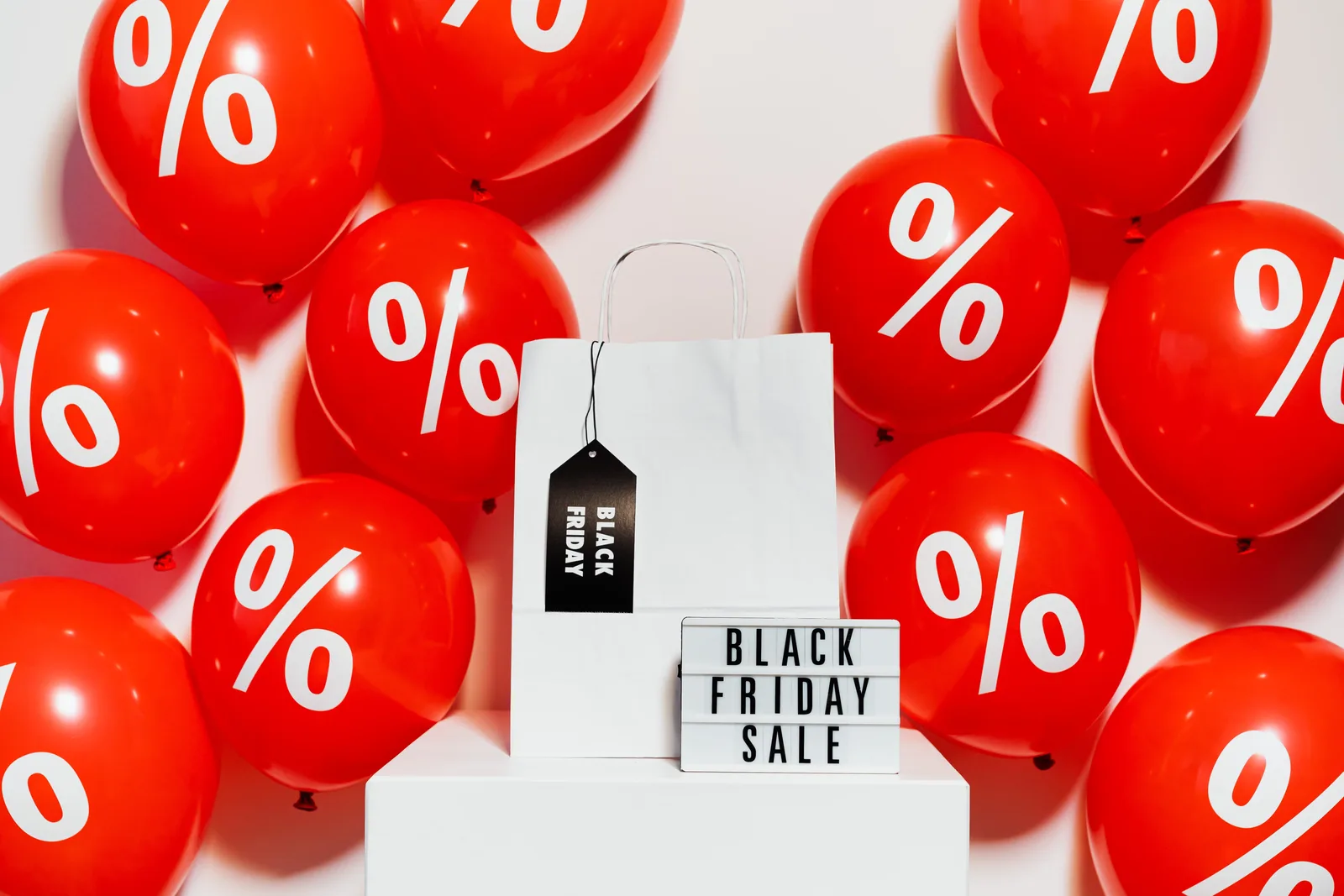 Vibrant Black Friday sale display with red balloons and a shopping bag showcasing discounts.