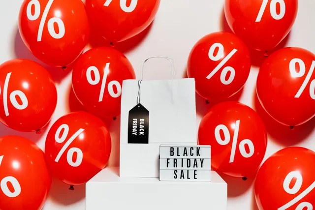 Vibrant Black Friday sale display with red balloons and a shopping bag showcasing discounts. Spedizione gratuita e sconto percentuale a confronto
